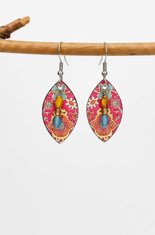 A pair of dangling earrings with silver fishhook wires and teardrop-shaped charms featuring a pink, red, and gold paisley pattern with small colorful bead accents.