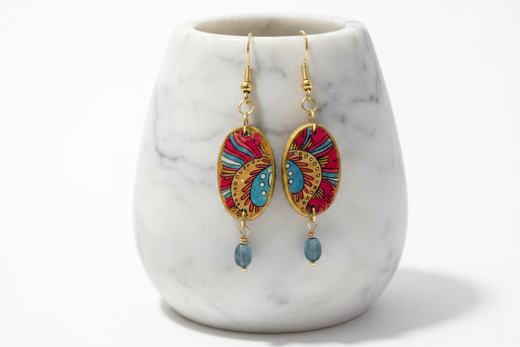A pair of bohemian oval drop earrings with gold-tone hooks and frames, featuring red, blue, and yellow hand-painted patterns, sealed with protective varnish  Hypoallergenic wires.