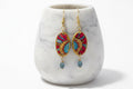 A pair of bohemian oval drop earrings with gold-tone hooks and frames, featuring red, blue, and yellow hand-painted patterns, sealed with protective varnish  Hypoallergenic wires.