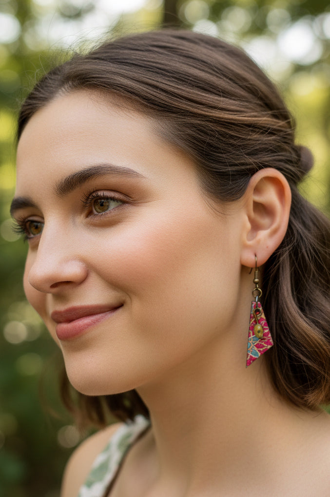 A pair of dangling earrings with triangular marbled patterns in  pink, red, green, and yellow, suspended from antiqued copper-toned wires.  Hypoallergenic for sensitive ears.