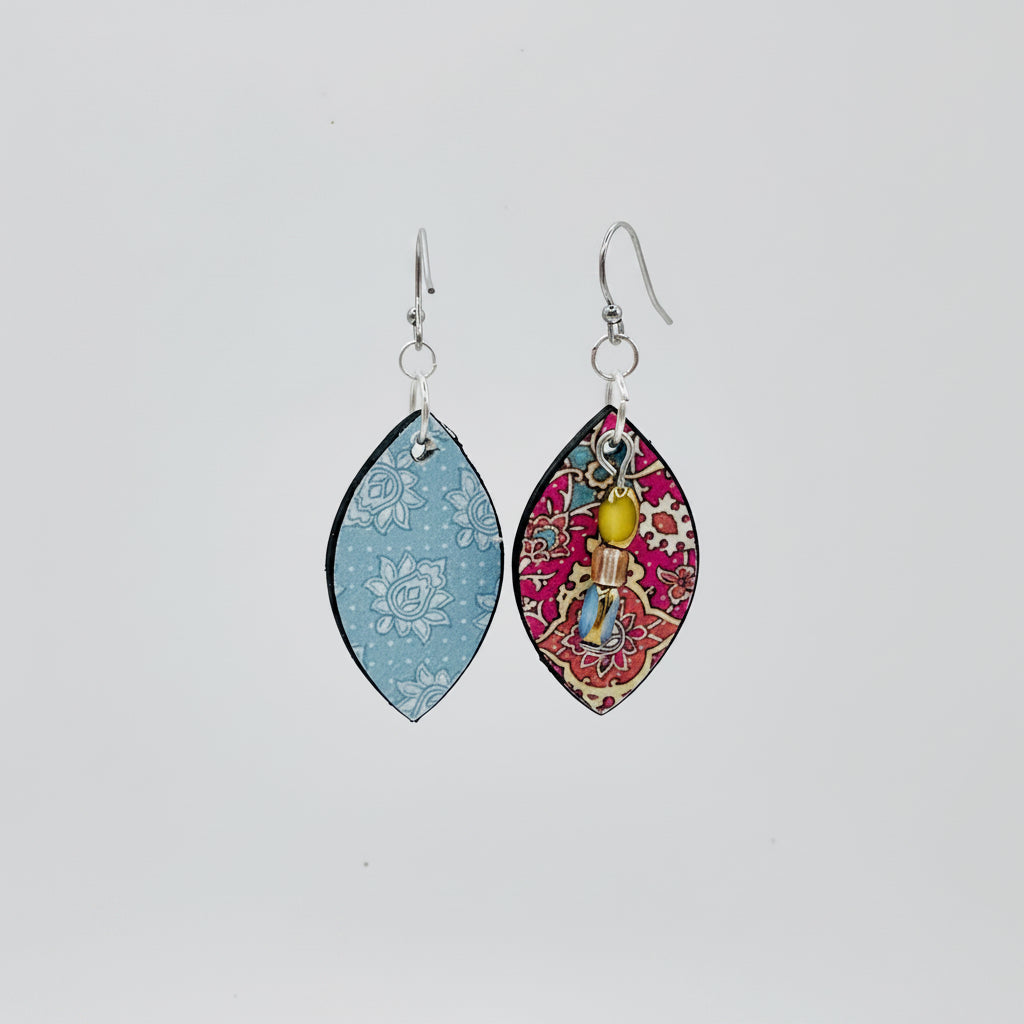 A pair of teardrop-shaped dangling earrings. Both earrings have  a red and gold paisley pattern.  The backs are a light blue background with white floral patterns.  