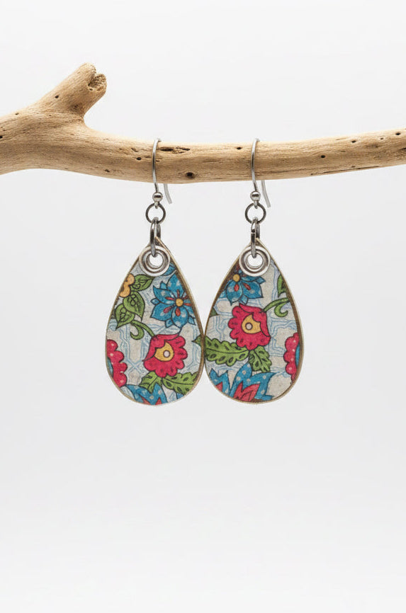 Teardrop-shaped dangle earrings with a colorful floral print on a light blue background, hanging from silver hypoallergenic hooks.