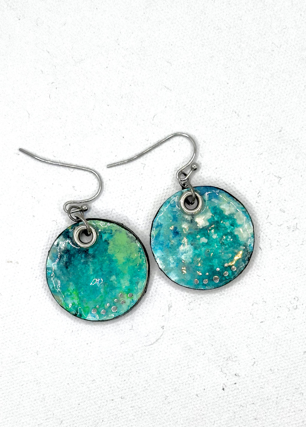 A pair of handmade round drop earrings featuring a marbled turquoise, teal, and green resin face with tiny gold & silver flecks.  Hypoallergenic silver fishhook wires.  Lightweight 