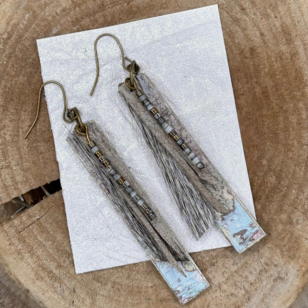 A pair of handmade dangle earrings with rectangular wood pieces covered with vintage maps, gray fur, recycled leather strips and small metallic beads. ;Hypoallergenic