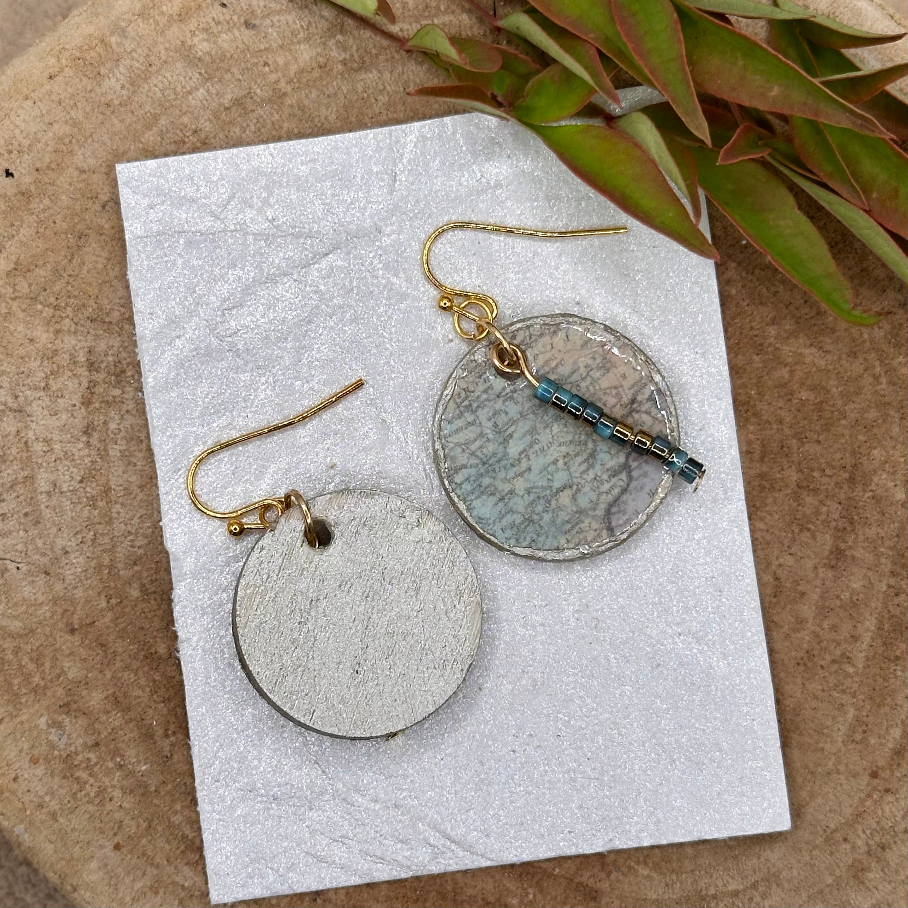 Handmade dangle earrings with a muted recycled map pattern, featuring small &nbsp;bead accents and silver tone hypoallergenic hooks.&nbsp; Sealed with a protective glaze.&nbsp; Light as a feather!