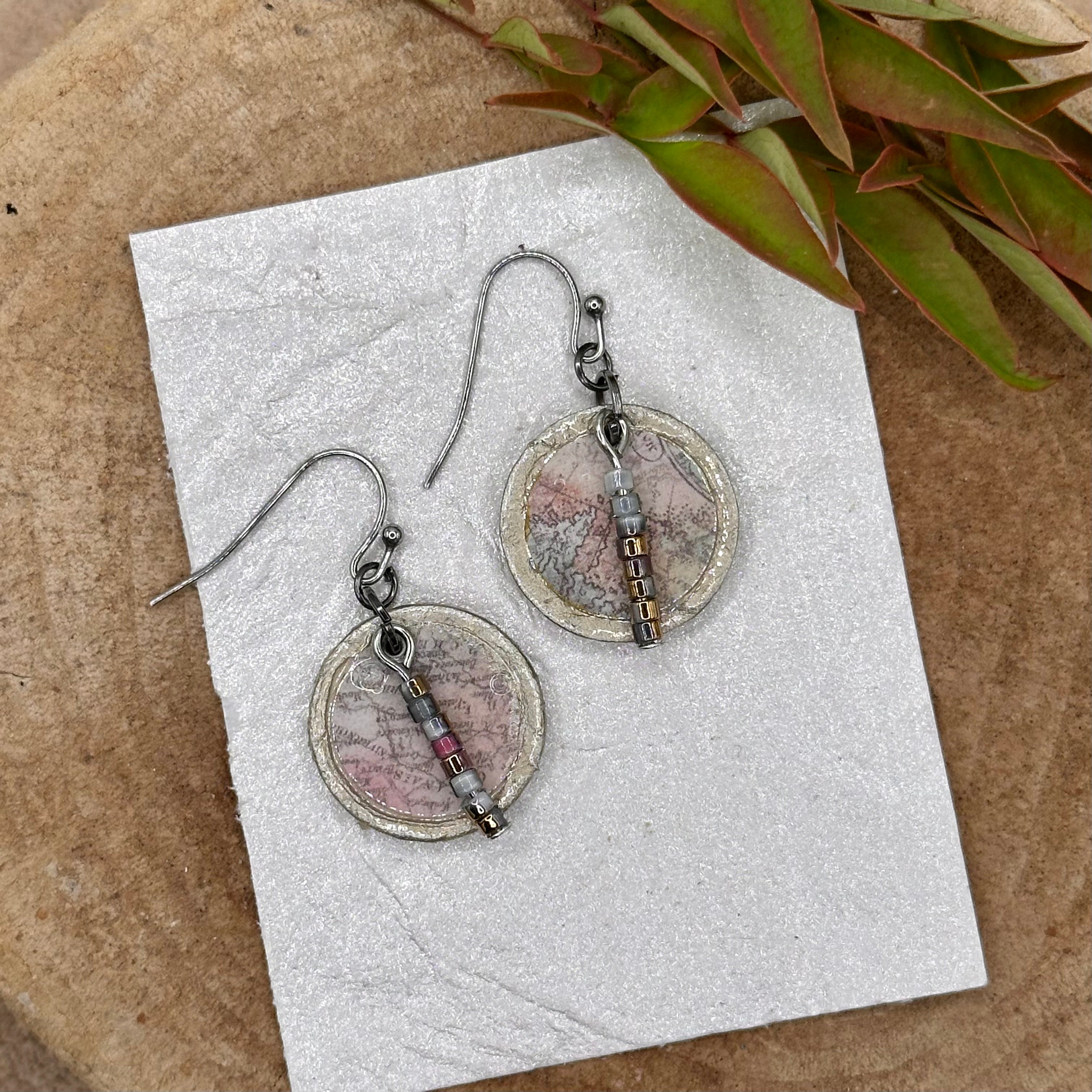 Handmade dangle earrings with a muted recycled map pattern, featuring small &nbsp;bead accents and silver tone hypoallergenic hooks.&nbsp; Sealed with a protective glaze.&nbsp; Light as a feather!
