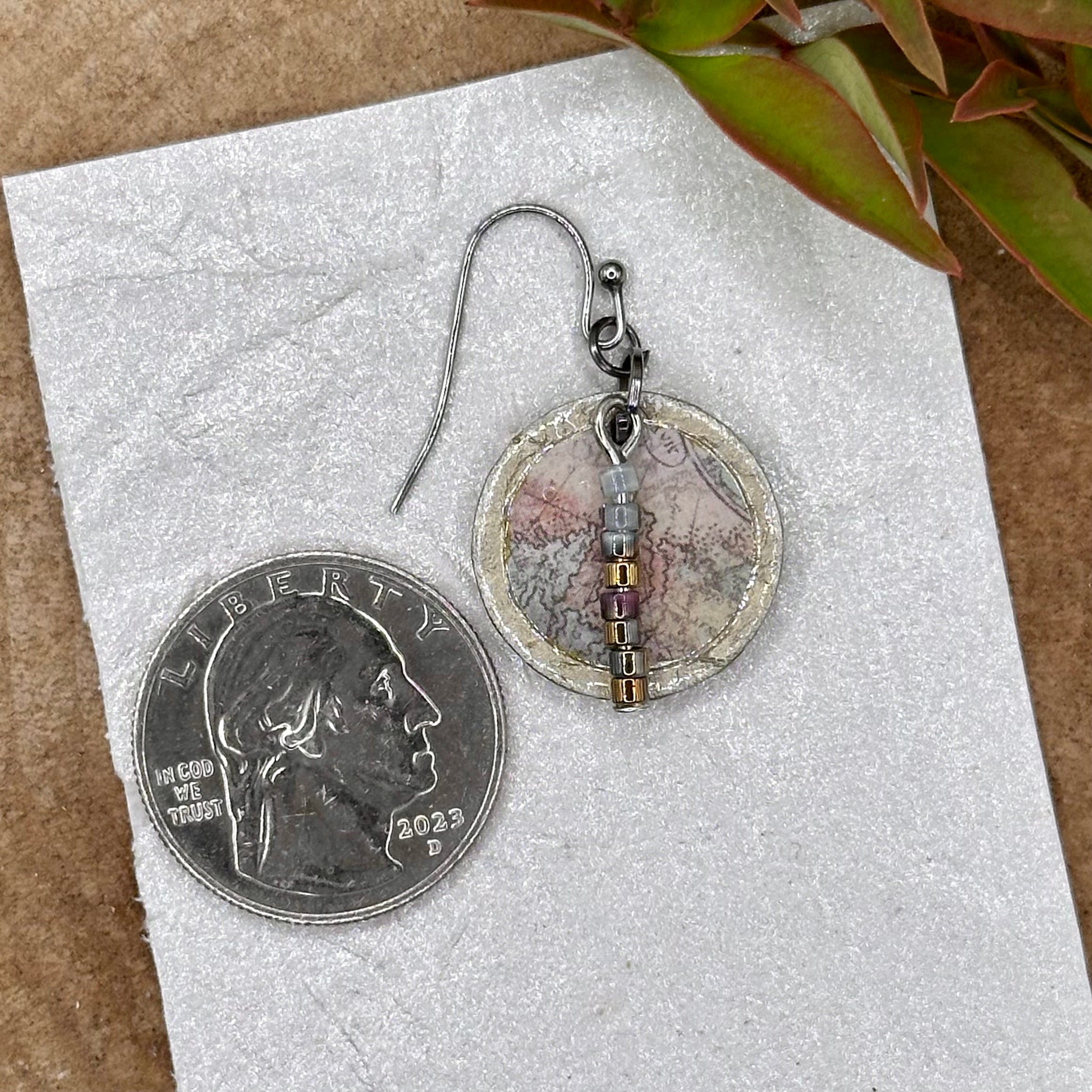 Handmade dangle earrings with a muted recycled map pattern, featuring small &nbsp;bead accents and silver tone hypoallergenic hooks.&nbsp; Sealed with a protective glaze.&nbsp; Light as a feather!
