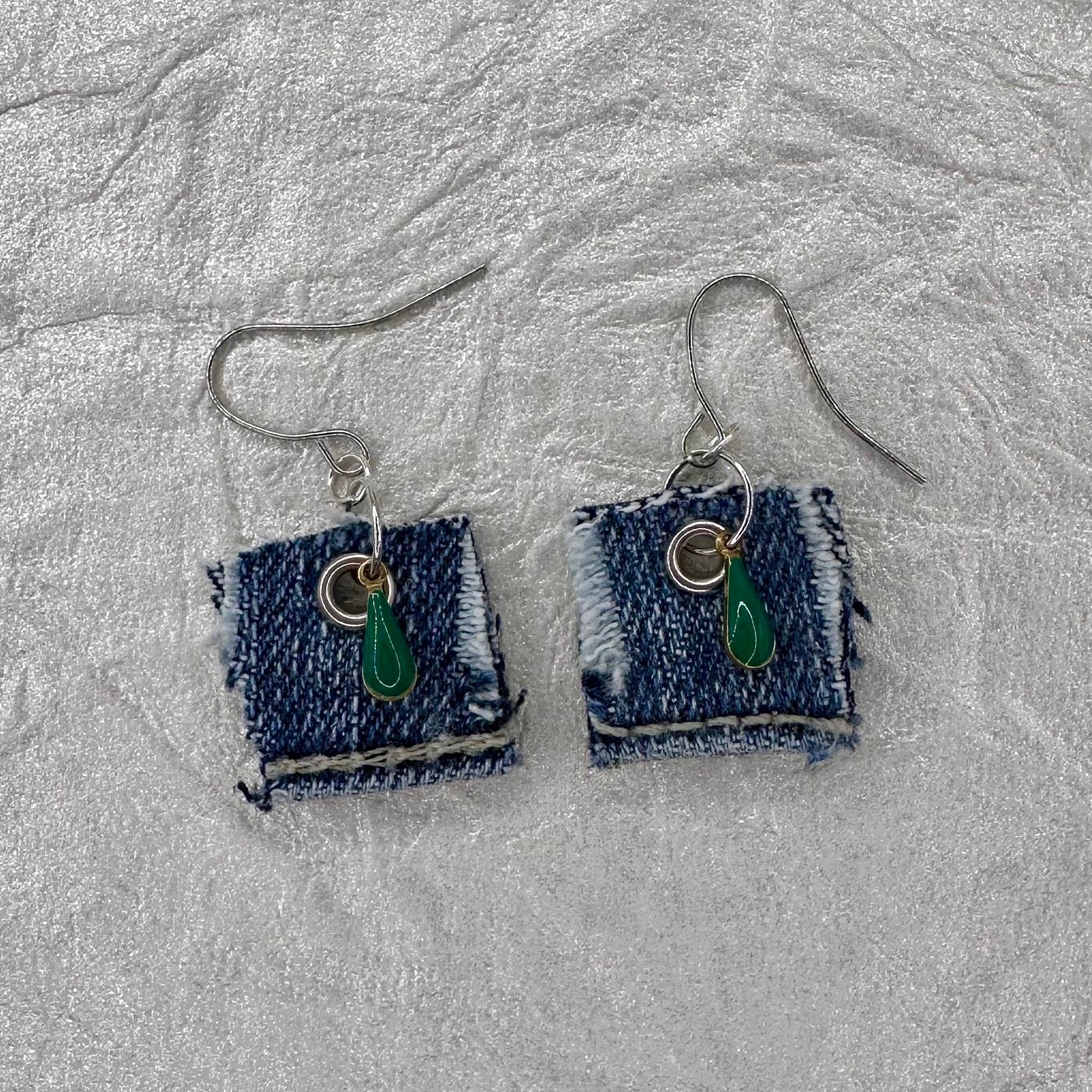 A pair of handmade square denim dangle earrings with silver fishhook wires and green teardrop charm.