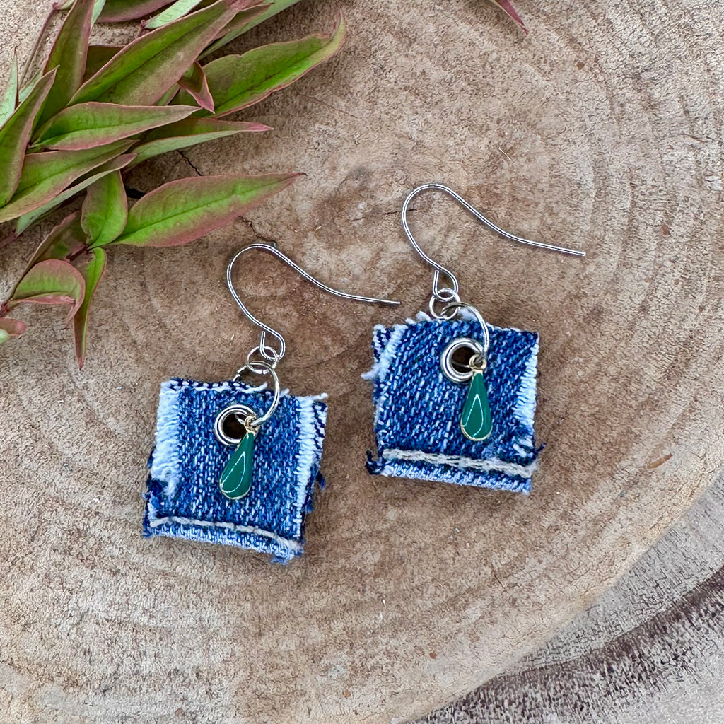 A pair of handmade square denim dangle earrings with silver fishhook wires and green teardrop charm.