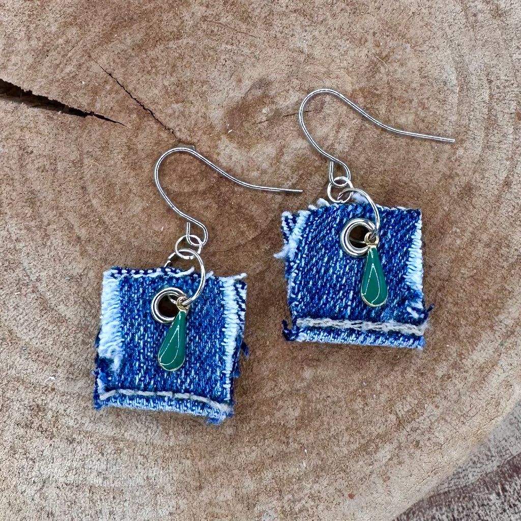 A pair of handmade square denim dangle earrings with silver fishhook wires and green teardrop charm.