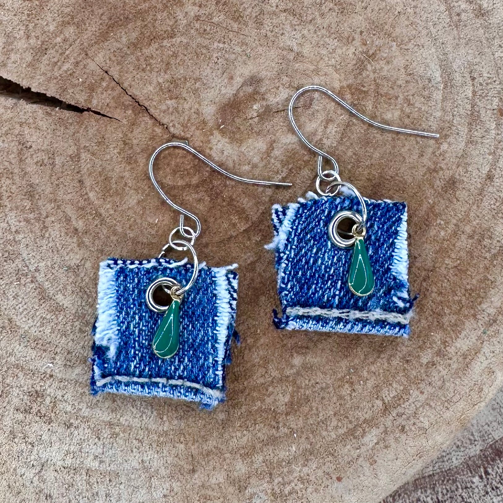 A pair of handmade square denim dangle earrings with silver fishhook wires and green teardrop charm.