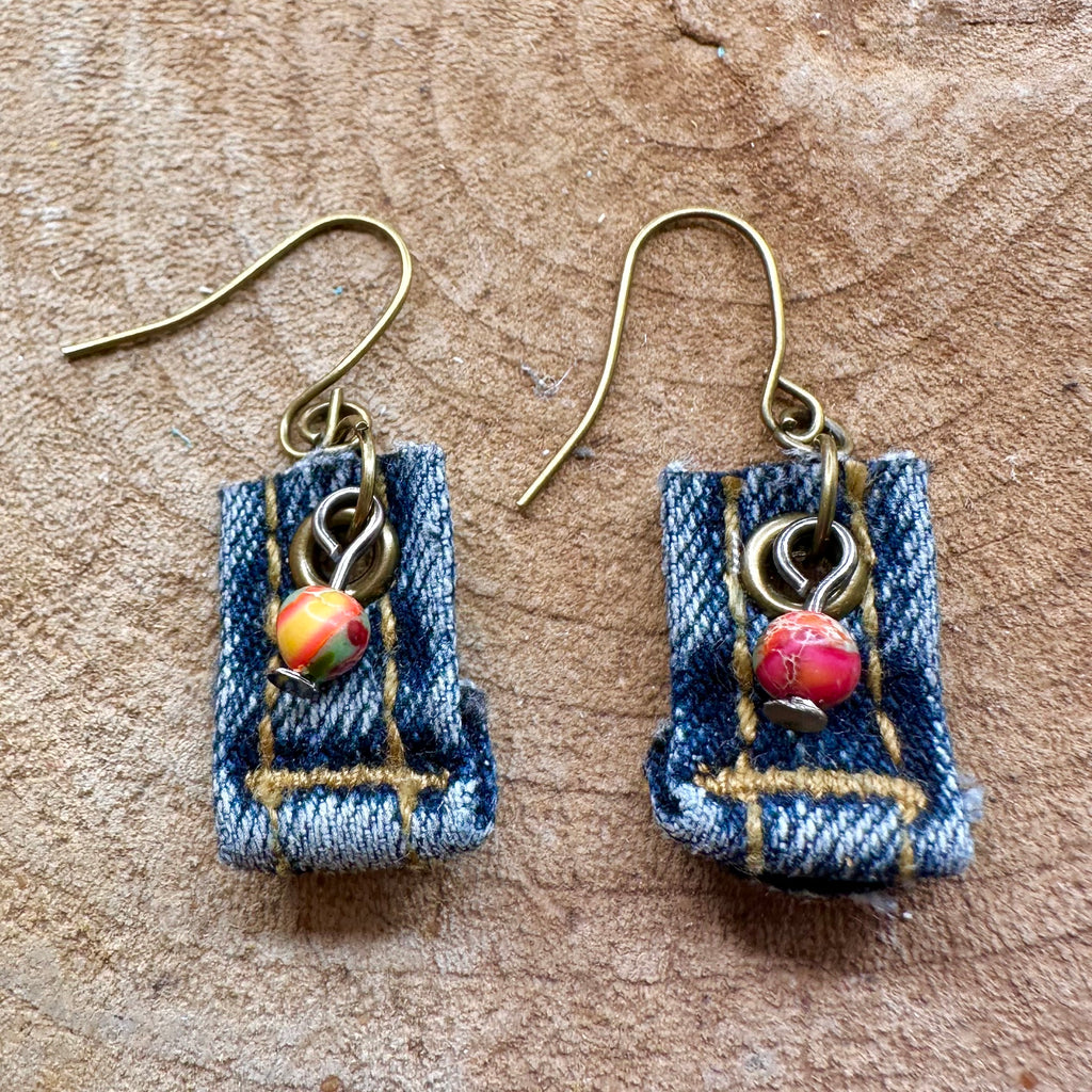 A pair of handmade dangle earrings made from blue denim fabric strips with vintage brass hypoallergenic metal hooks and small colorful bead charms.  .75” long without hooks