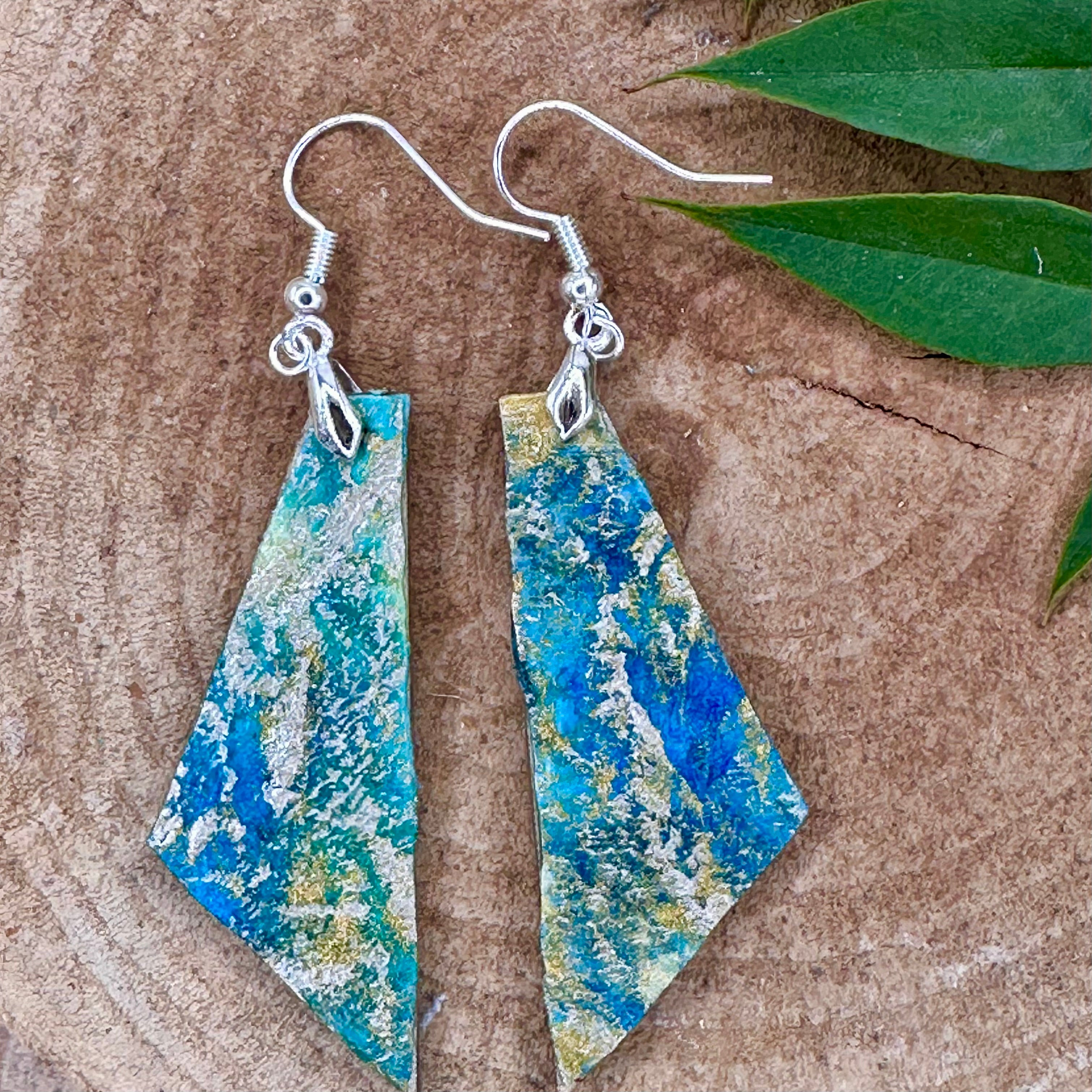 Hand painted geometric earrings in marbled teal, green, and gold textured with silver-tone fishhook wires. Sealed with a protective mat varnish. &nbsp;Hypoallergenic and light as a feather.&nbsp; &nbsp;2” long not including earring wire.