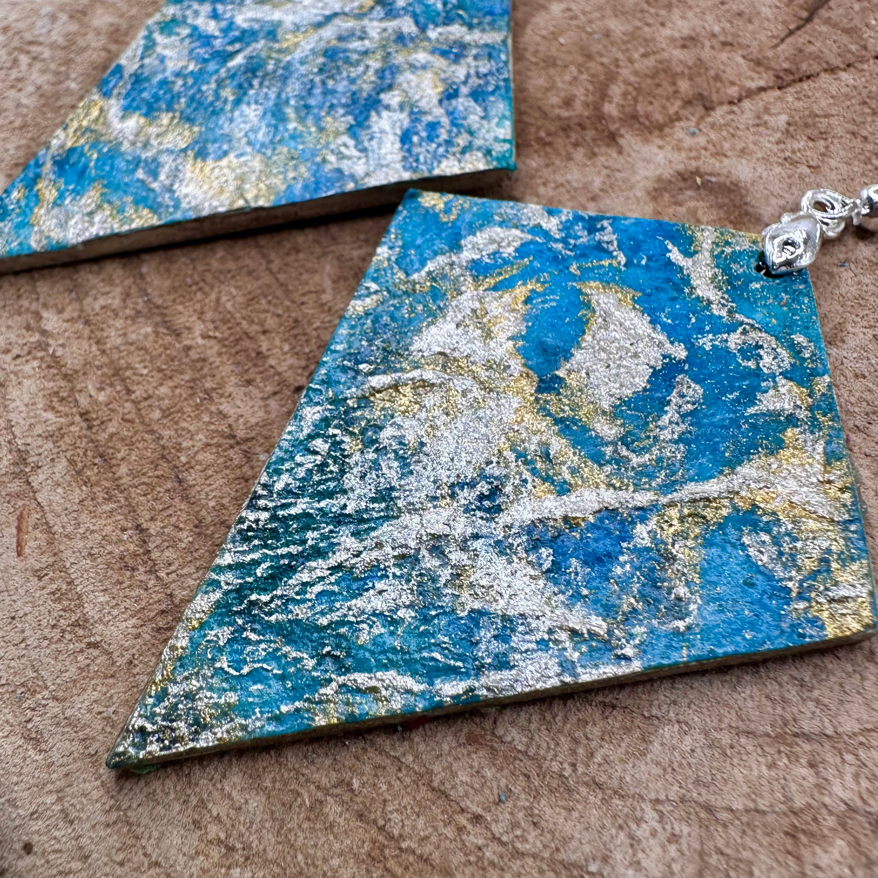 Hand painted earrings in marbled teal, green, and gold textured with silver-tone fishhook wires and diamond-shaped pendants. Sealed with a protective mat varnish.  Hypoallergenic and light as a feather. 2" long not including the earring
