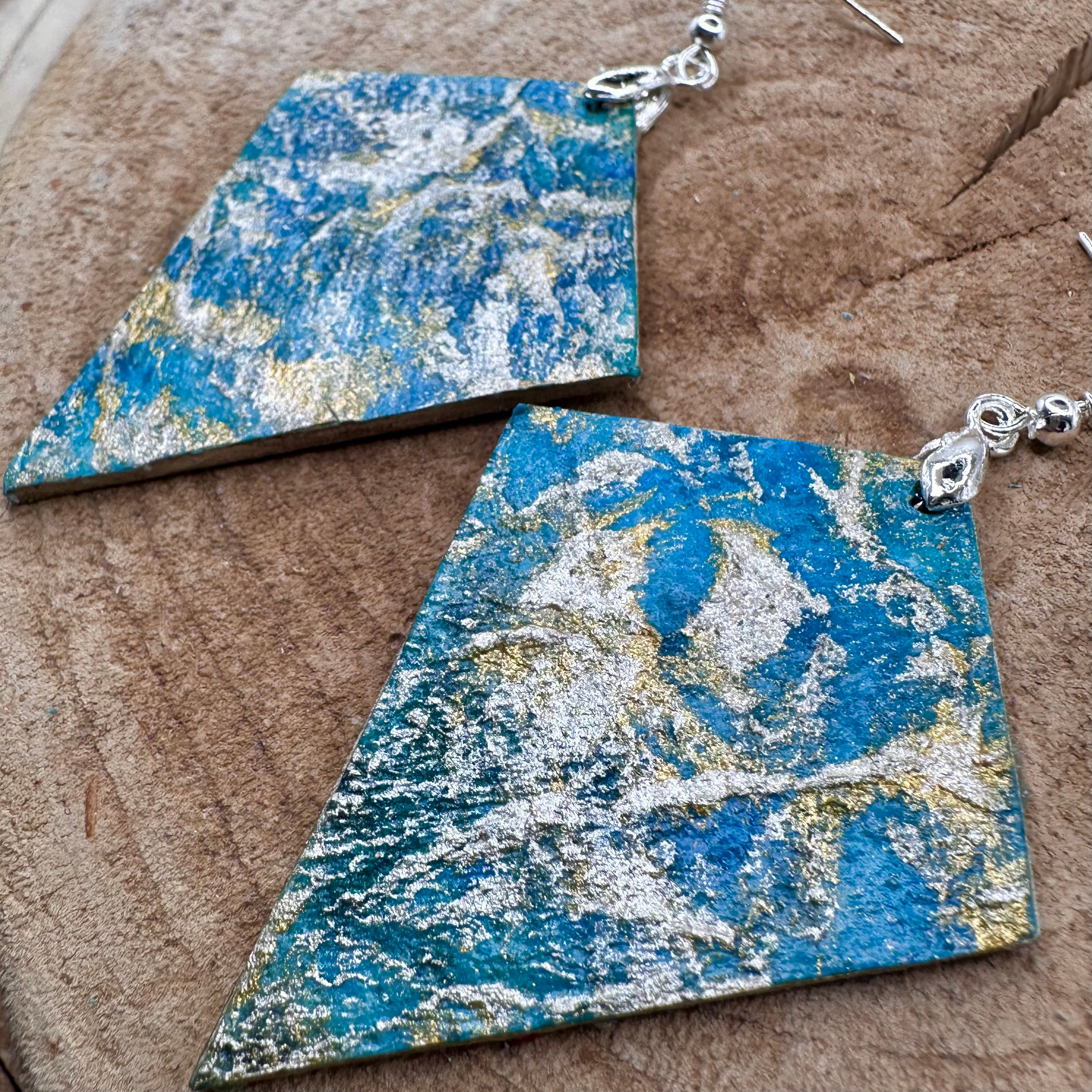 Hand painted earrings in marbled teal, green, and gold textured with silver-tone fishhook wires and diamond-shaped pendants. Sealed with a protective mat varnish. &nbsp;Hypoallergenic and light as a feather.&nbsp; 2” long not including earring wire