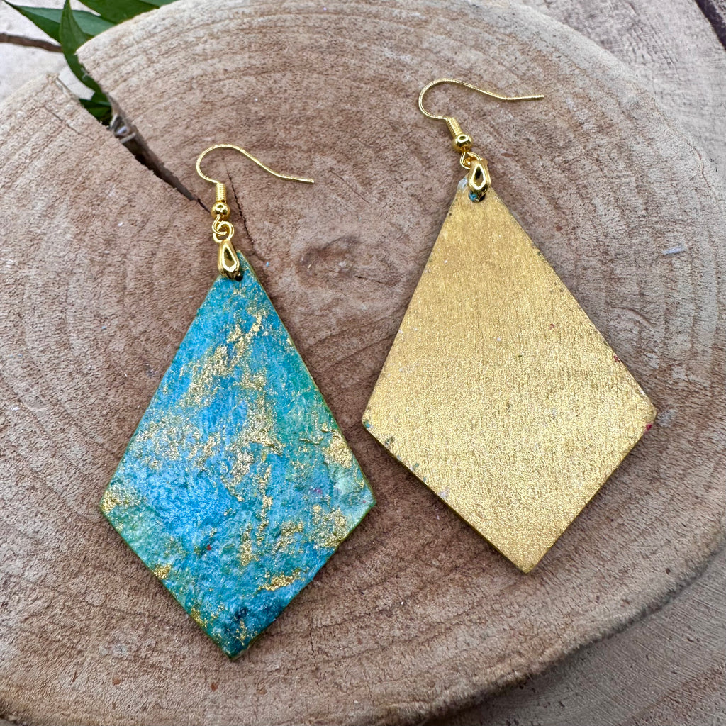 Hand painted earrings in marbled teal, green, and gold textured with gold-tone fishhook wires and diamond-shaped pendants. Sealed with a protective mat varnish. Hypoallergenic and light as a feather. 2” long not including earring wire.