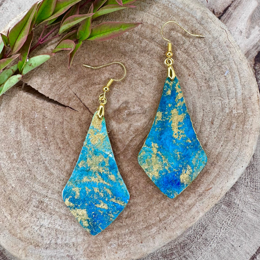 Hand painted earrings in marbled teal, green, and gold textured with gold-tone fishhook wires and diamond-shaped pendants. Sealed with a protective mat varnish. Hypoallergenic and light as a feather.  2” long not including earring wire.