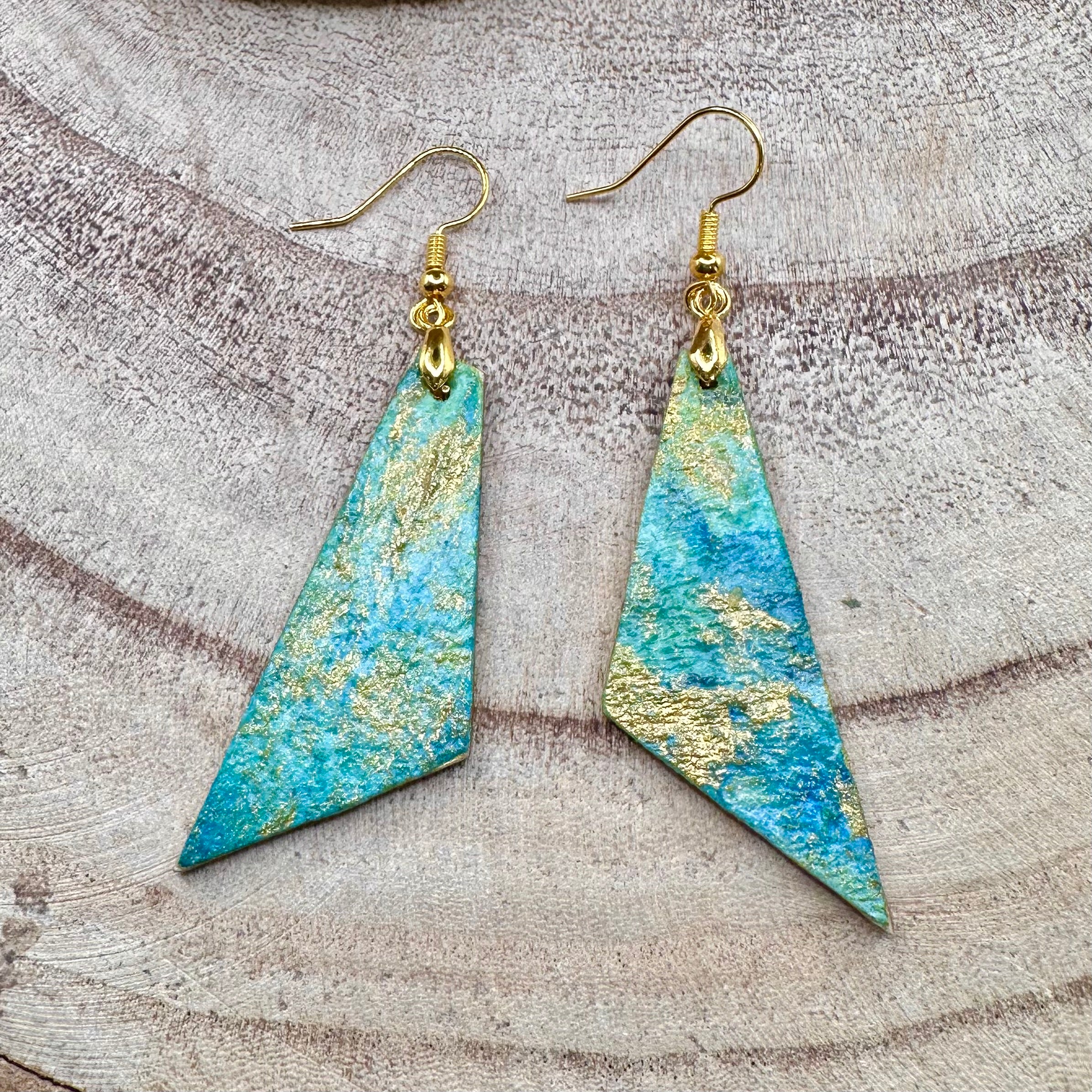 Hand painted earrings in marbled teal, green, and gold textured with gold-tone fishhook wires. Sealed with a protective mat varnish. &nbsp;Hypoallergenic and light as a feather.&nbsp; &nbsp;2” long not including earring wire.